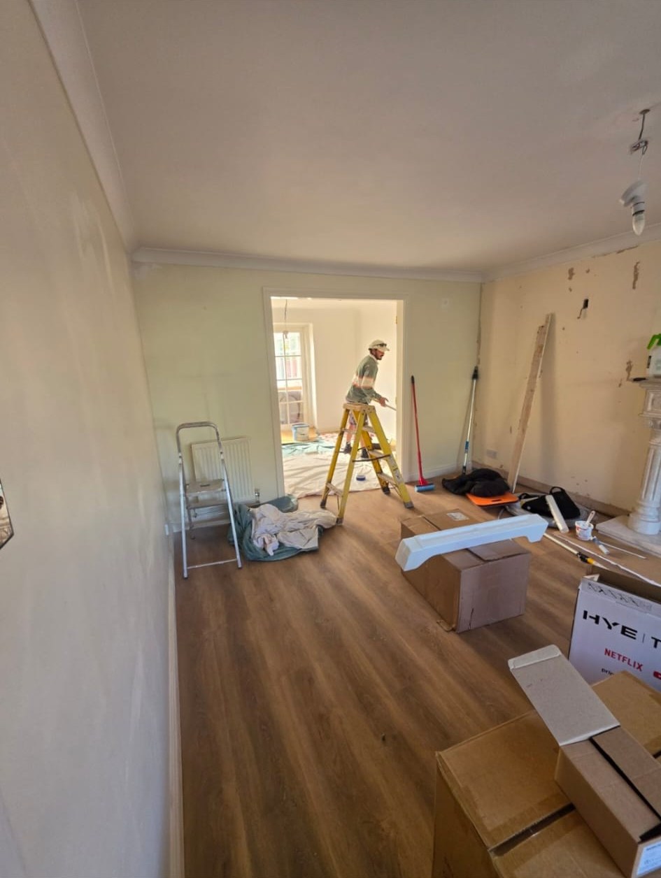 Empty room being decorated before staging, with a decorator on a ladder